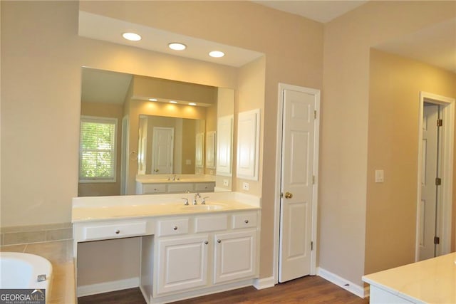 bathroom featuring vanity, hardwood / wood-style flooring, and a tub to relax in