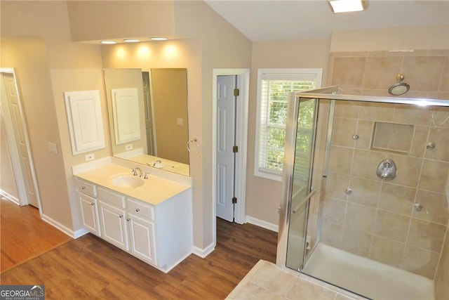 bathroom with vanity, vaulted ceiling, wood-type flooring, and a shower with shower door