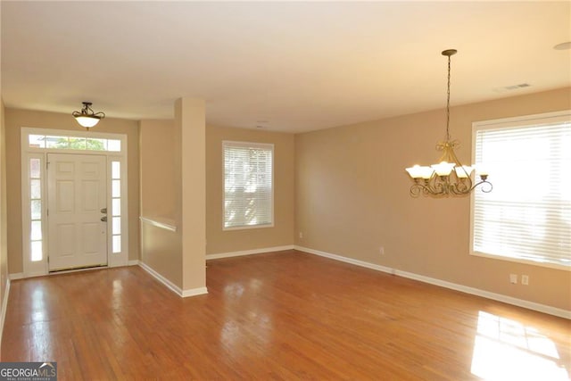 foyer with an inviting chandelier, hardwood / wood-style floors, and a healthy amount of sunlight