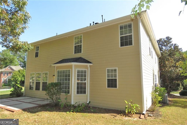 rear view of house with a patio area, central AC unit, and a lawn