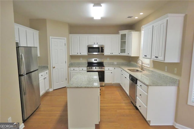 kitchen with sink, a center island, white cabinetry, light hardwood / wood-style floors, and stainless steel appliances