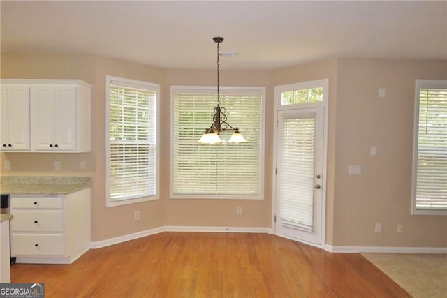 unfurnished dining area featuring light hardwood / wood-style floors and a chandelier