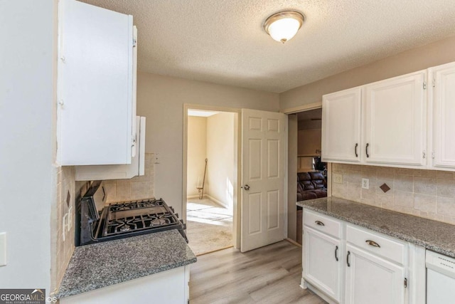 kitchen featuring decorative backsplash, white cabinets, a textured ceiling, light wood-type flooring, and black range