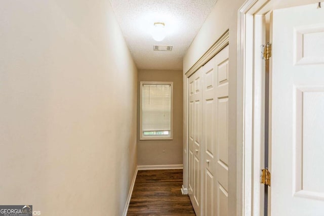 hall featuring a textured ceiling and dark hardwood / wood-style flooring