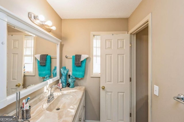 bathroom featuring vanity, a healthy amount of sunlight, and a textured ceiling