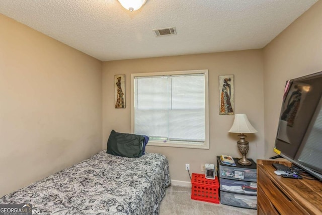 bedroom featuring a textured ceiling and light colored carpet