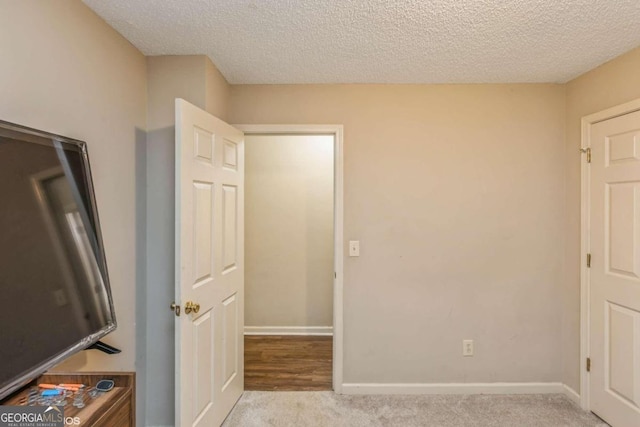 unfurnished bedroom featuring light carpet and a textured ceiling