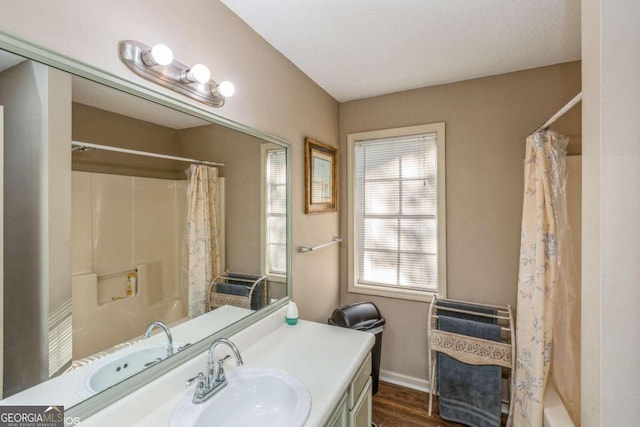 bathroom featuring vanity, a textured ceiling, shower / bath combo with shower curtain, and wood-type flooring