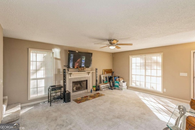 carpeted living room with a textured ceiling, a fireplace, and ceiling fan