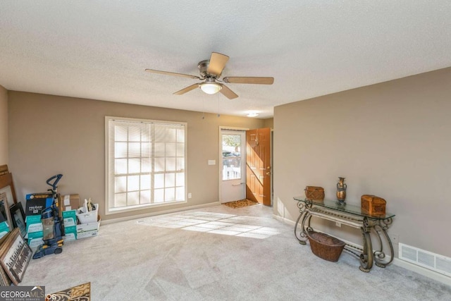 doorway with light carpet, a textured ceiling, and ceiling fan