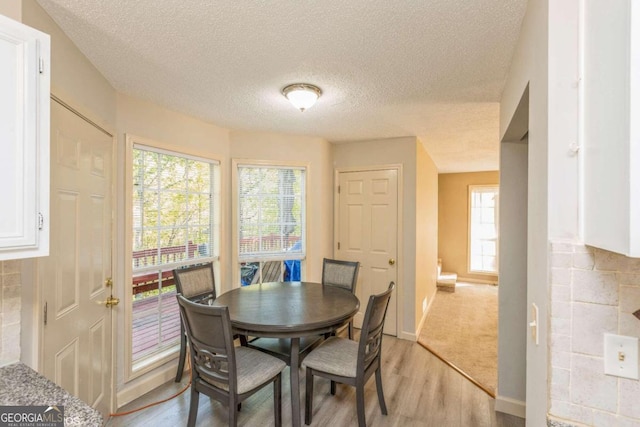 dining area featuring a textured ceiling and light hardwood / wood-style flooring