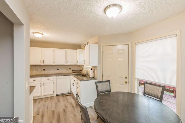 kitchen featuring tasteful backsplash, white cabinetry, light wood-type flooring, dishwasher, and sink