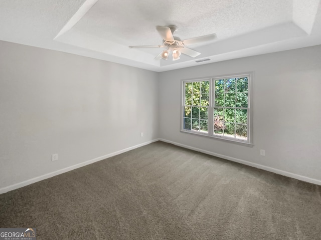 carpeted spare room featuring ceiling fan, a textured ceiling, and a raised ceiling