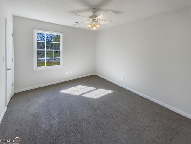 empty room featuring ceiling fan and dark carpet