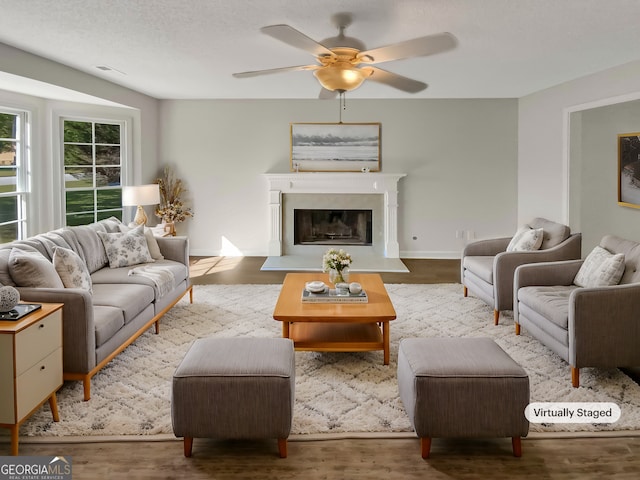 living room featuring a textured ceiling, wood-type flooring, and ceiling fan