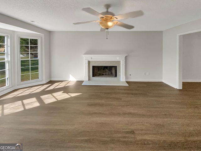 unfurnished living room with ceiling fan, a textured ceiling, and dark colored carpet