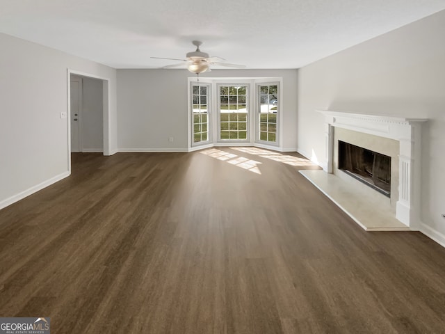 unfurnished living room featuring dark wood-type flooring and ceiling fan