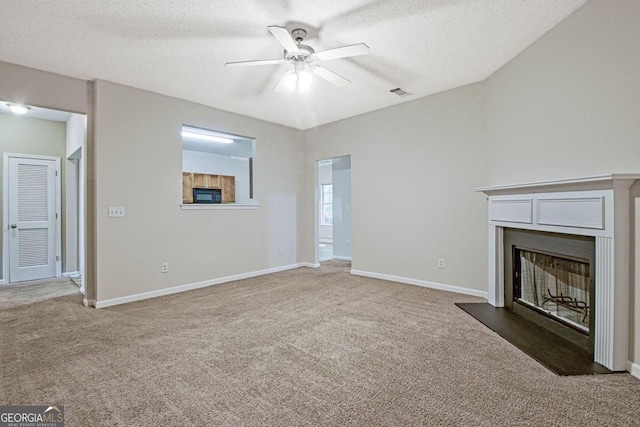 unfurnished living room with ceiling fan, a textured ceiling, and carpet floors