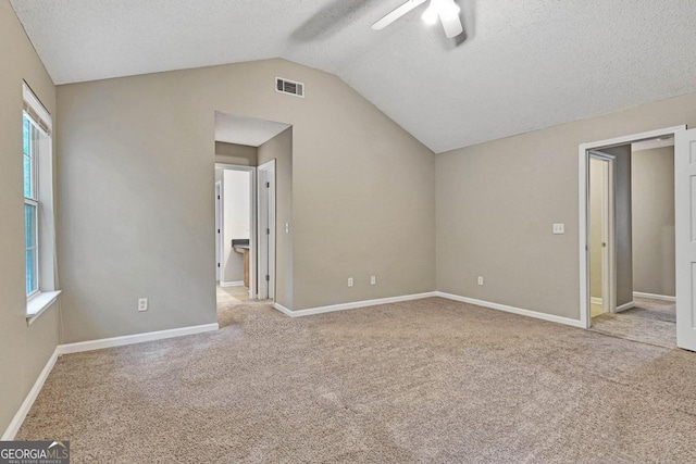 interior space with lofted ceiling, light carpet, a textured ceiling, and ceiling fan