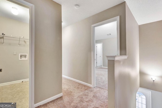 hall with a textured ceiling, vaulted ceiling, and light colored carpet