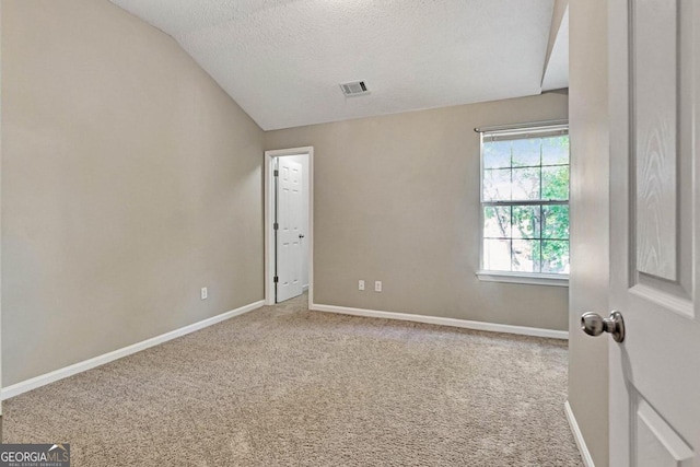 carpeted spare room with a textured ceiling and vaulted ceiling