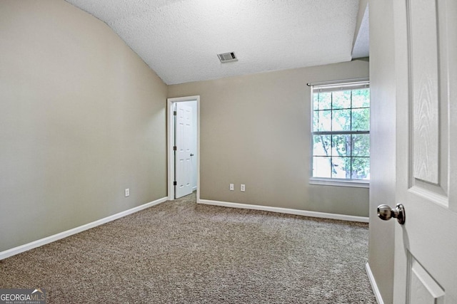 empty room with a textured ceiling, vaulted ceiling, and carpet floors