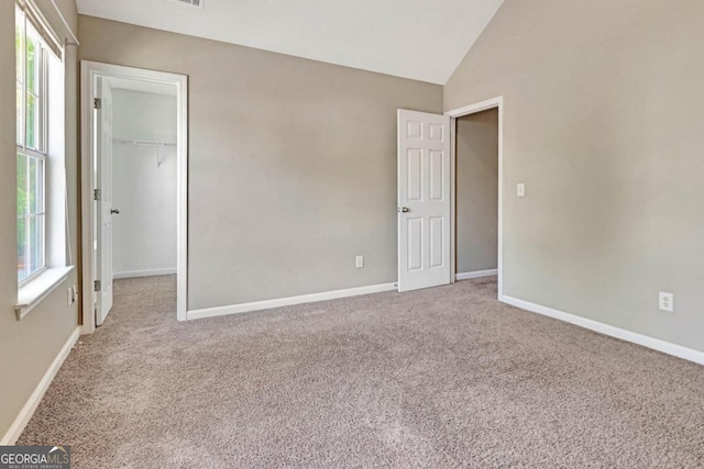 empty room featuring vaulted ceiling, carpet floors, and plenty of natural light