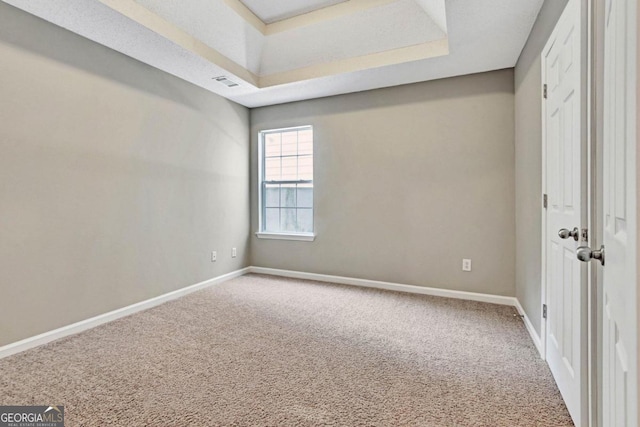 unfurnished room featuring carpet and a raised ceiling