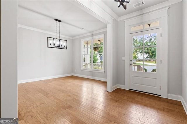 doorway featuring ornamental molding, hardwood / wood-style flooring, a chandelier, and a wealth of natural light