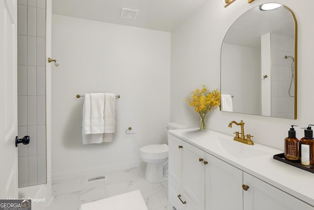 bathroom featuring toilet, vanity, and a tile shower