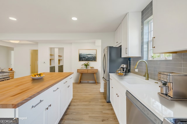 kitchen featuring light hardwood / wood-style flooring, sink, white cabinets, appliances with stainless steel finishes, and tasteful backsplash