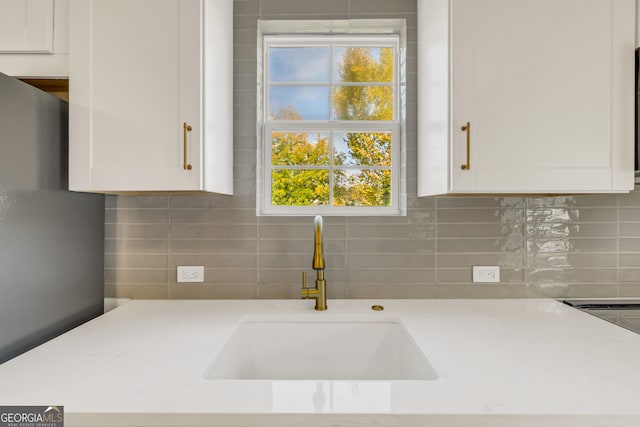 kitchen with white cabinets, tasteful backsplash, and sink