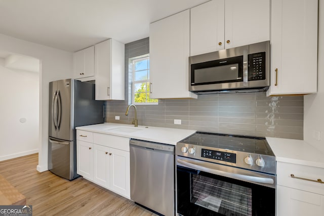 kitchen featuring tasteful backsplash, sink, stainless steel appliances, white cabinets, and light hardwood / wood-style flooring