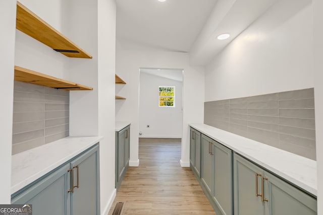 kitchen featuring backsplash, light stone countertops, and light wood-type flooring