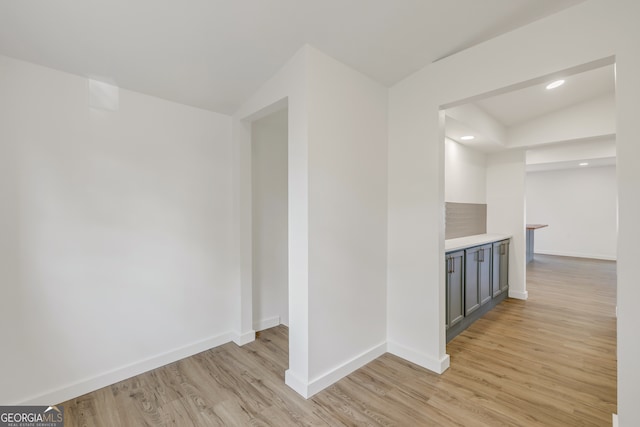 corridor with vaulted ceiling and light hardwood / wood-style flooring