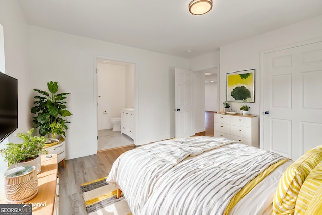 bedroom with ensuite bath and light wood-type flooring