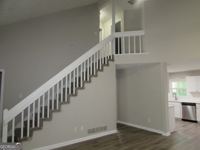 stairs with lofted ceiling, sink, and hardwood / wood-style flooring