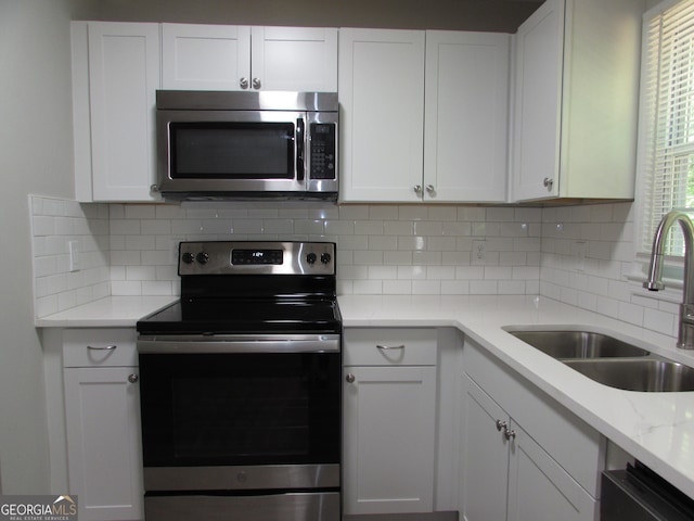 kitchen with appliances with stainless steel finishes, white cabinetry, and sink