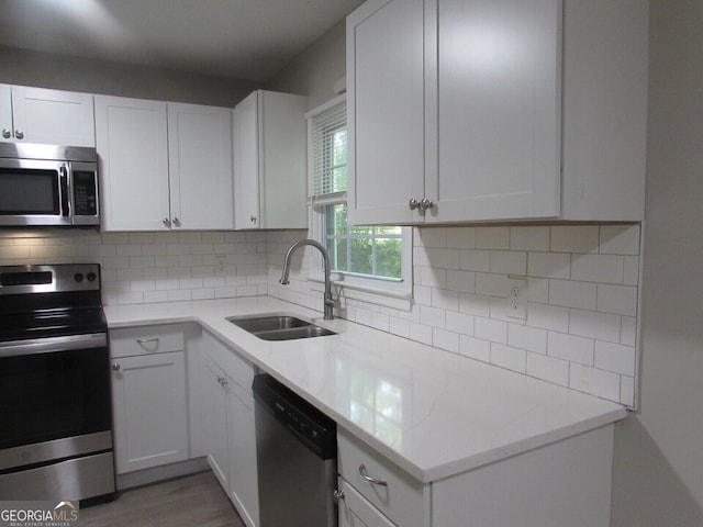 kitchen with appliances with stainless steel finishes, white cabinets, sink, and backsplash