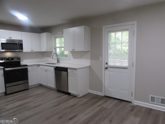 kitchen with white cabinetry, stainless steel appliances, backsplash, and dark hardwood / wood-style flooring