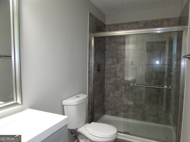 bathroom with a shower with door, vanity, a textured ceiling, and toilet