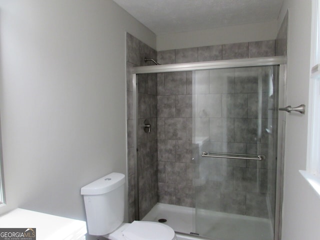 bathroom featuring toilet and a shower with shower door