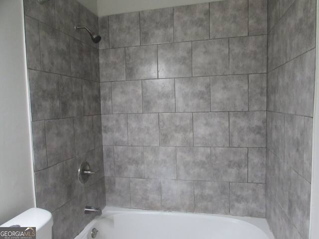 bathroom featuring toilet and tiled shower / bath combo