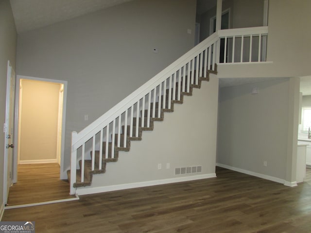 stairs featuring hardwood / wood-style floors and high vaulted ceiling