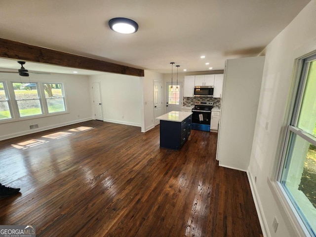 kitchen featuring dark hardwood / wood-style flooring, appliances with stainless steel finishes, a kitchen island, white cabinetry, and decorative light fixtures