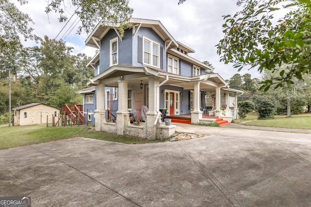 view of front of property with covered porch, a front yard, and a shed