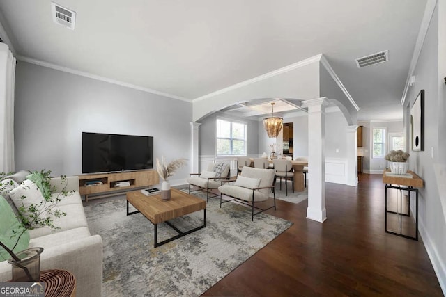 living room featuring a chandelier, dark hardwood / wood-style floors, ornate columns, and crown molding