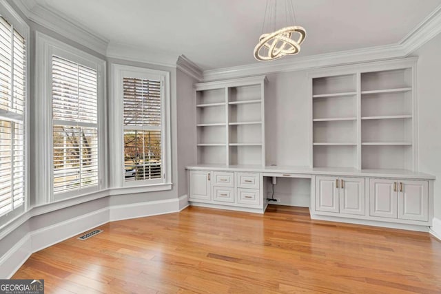 interior space featuring light hardwood / wood-style floors, ornamental molding, built in desk, and a wealth of natural light