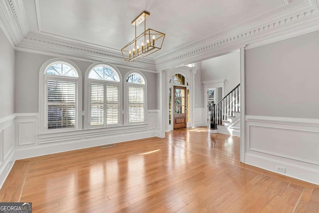 interior space featuring an inviting chandelier, ornamental molding, and light wood-type flooring