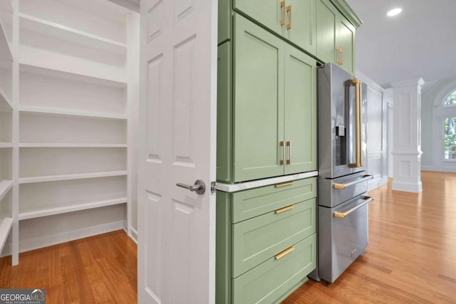 interior space with light hardwood / wood-style flooring, stainless steel fridge, green cabinetry, and ornate columns